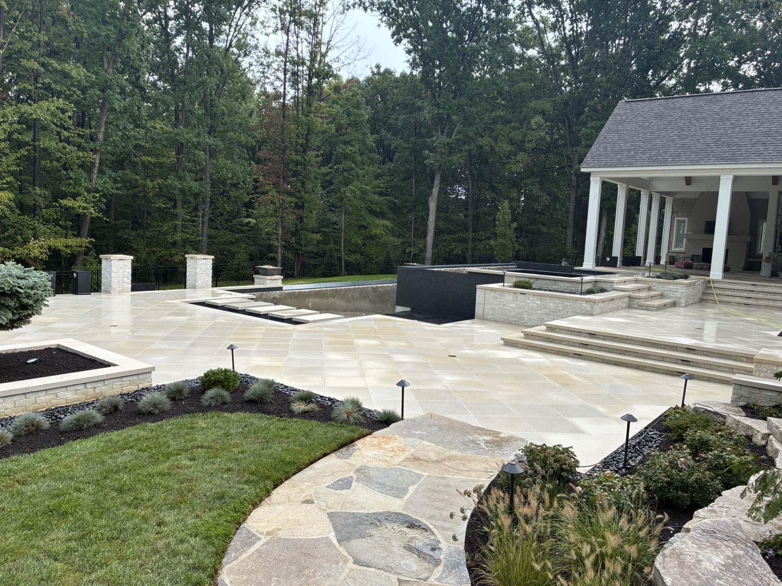 Luxury stone patio and landscaped outdoor living space by Northwood Landscape